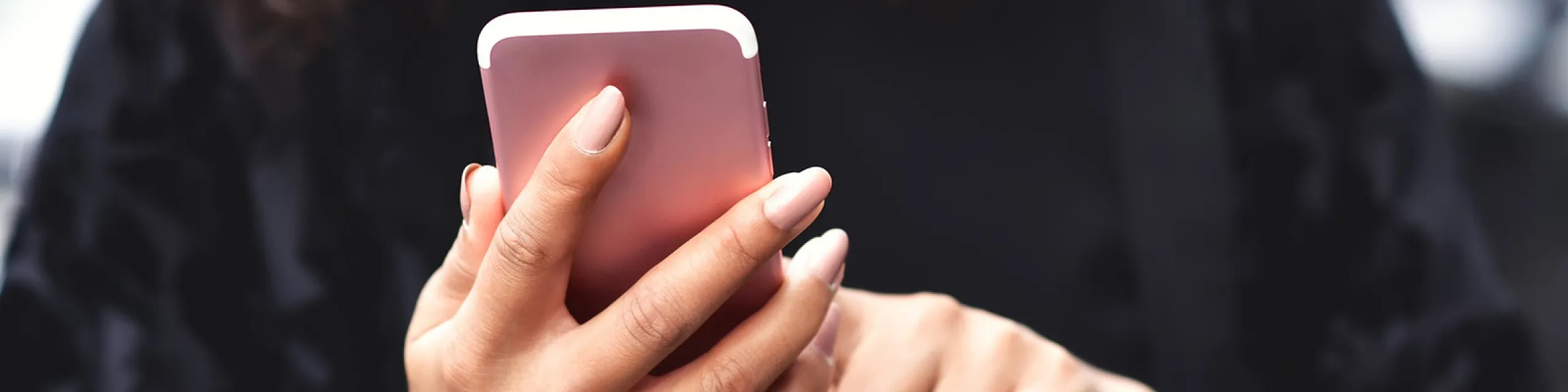 Close-up of a woman browsing on a stylish pink smartphone, showcasing elegance and modern tech connectivity.