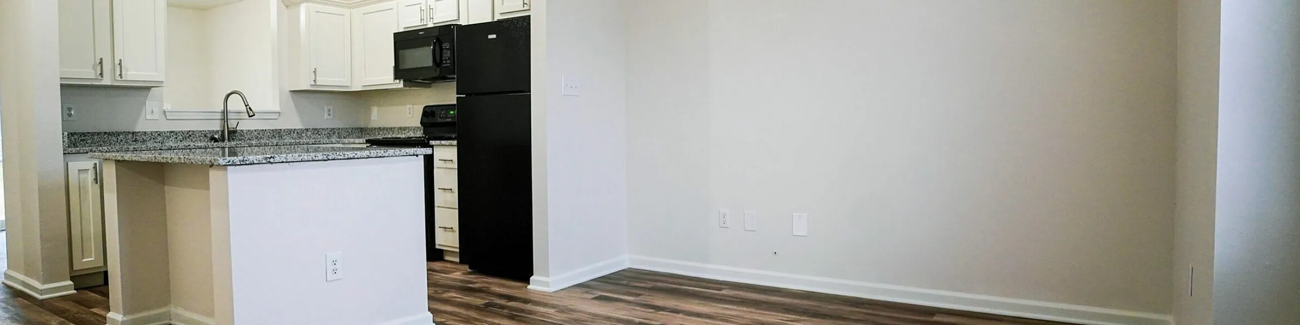 Bright open-concept kitchen with sleek granite countertops, modern white cabinetry, and rich hardwood floors.