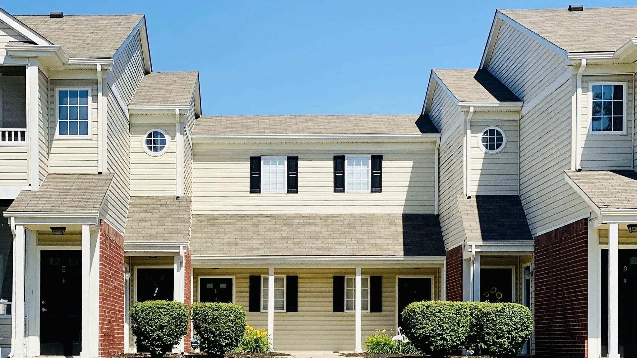 Charming townhouse facade showcasing modern architecture with clean lines and inviting entryways, surrounded by well-maintained landscaping.