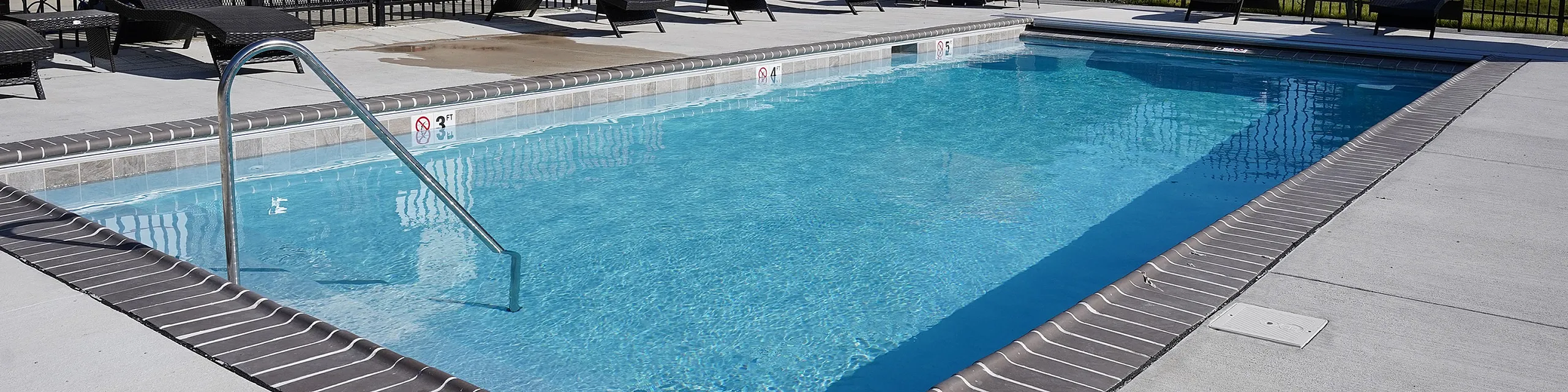 Inviting outdoor pool area with cozy lounge chairs and umbrella, perfect for relaxation and enjoyment under clear blue skies.