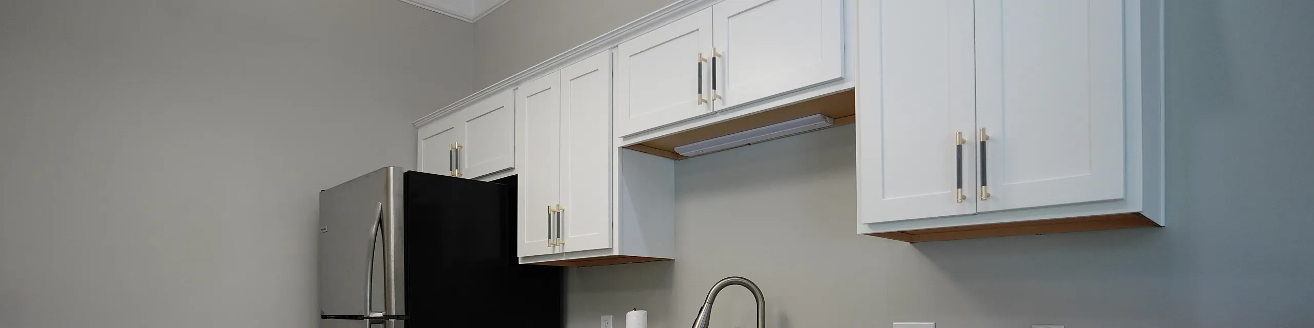 Modern kitchen with elegant granite countertops, sleek stainless steel fridge, and stylish white cabinetry.