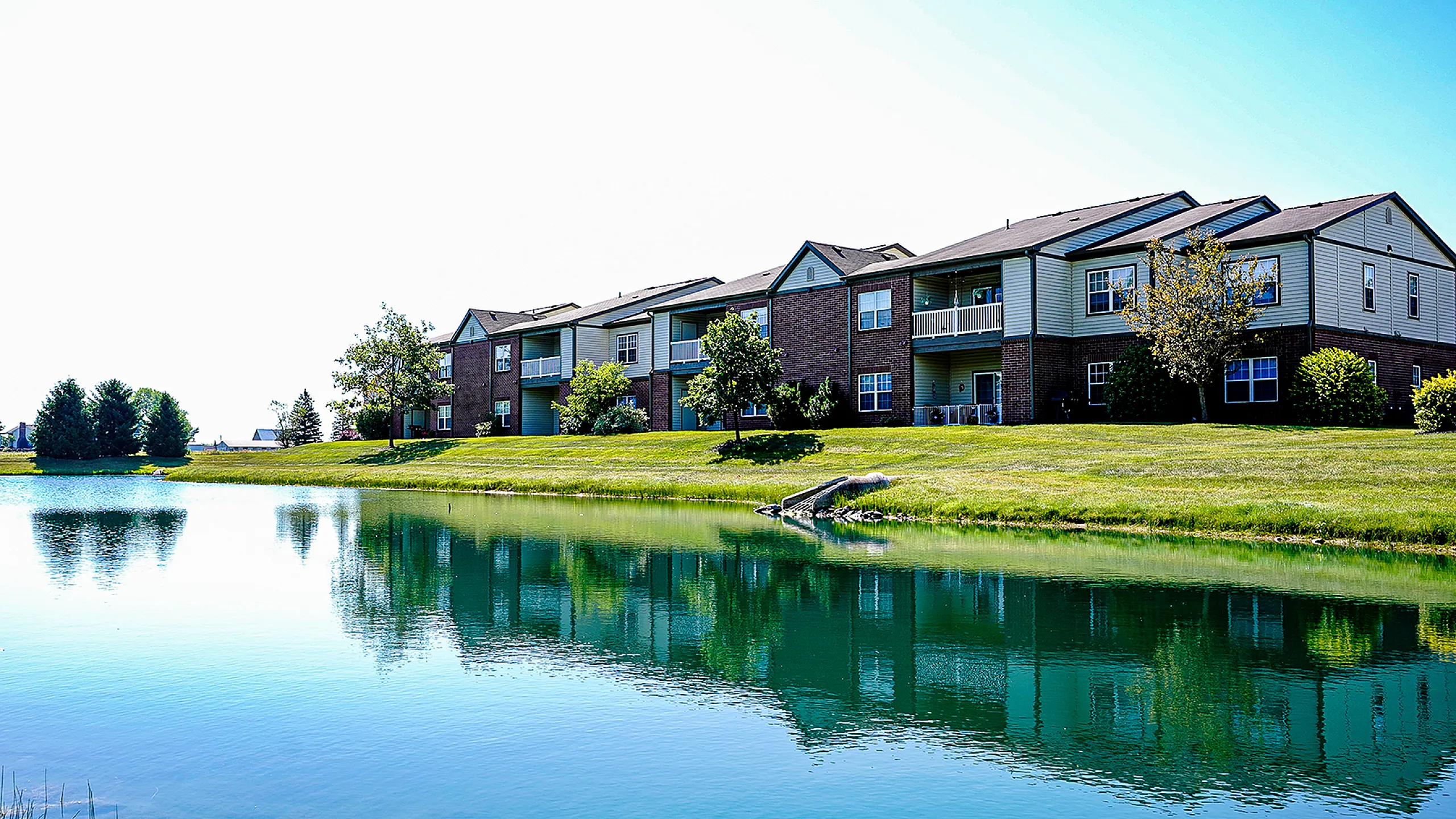 Picturesque apartment complex with charming lake views and lush greenery, offering serene living in a beautiful setting.