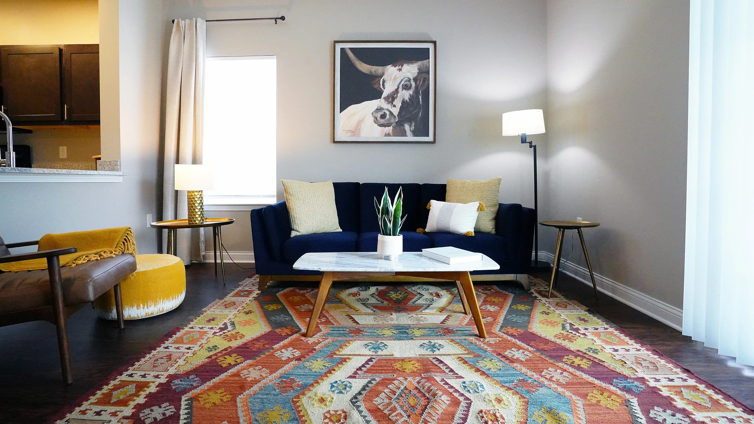 Chic living room featuring a vibrant patterned rug, plush navy sofa, and elegant decor with a modern aesthetic.
