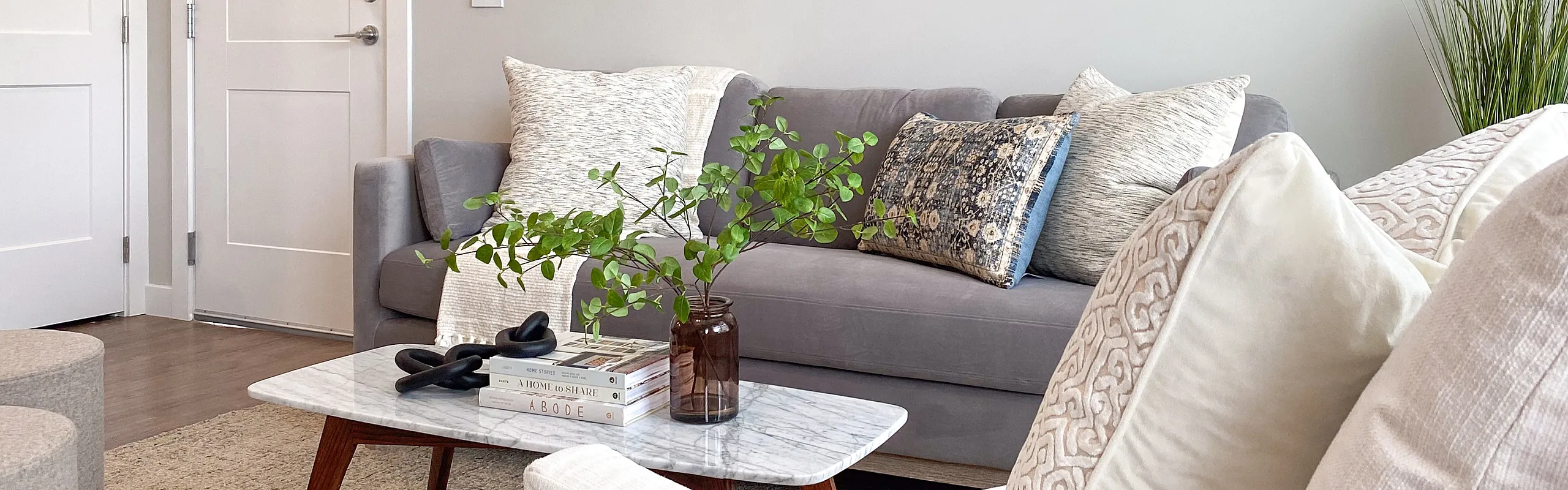 Chic and cozy living room with elegant decor, featuring a plush gray sofa, modern art on the walls, and a stylish marble coffee table.