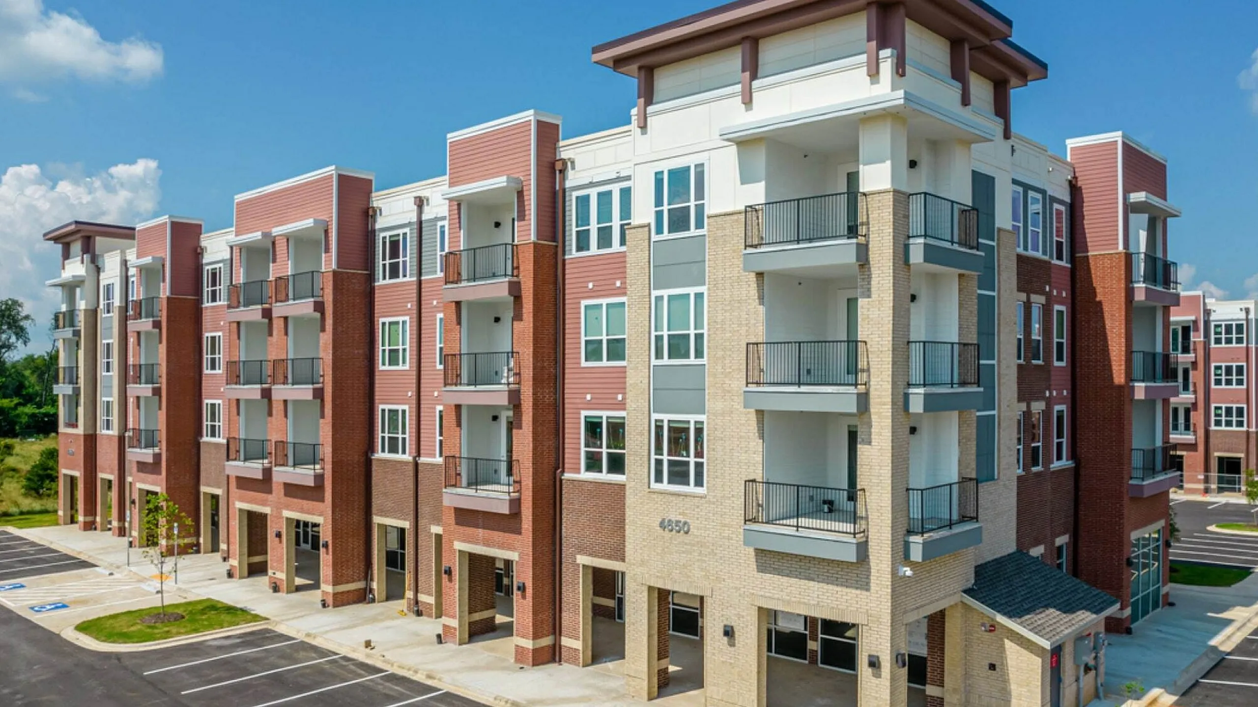 Modern apartment complex with spacious balconies and stylish brick facade, offering premium urban living.