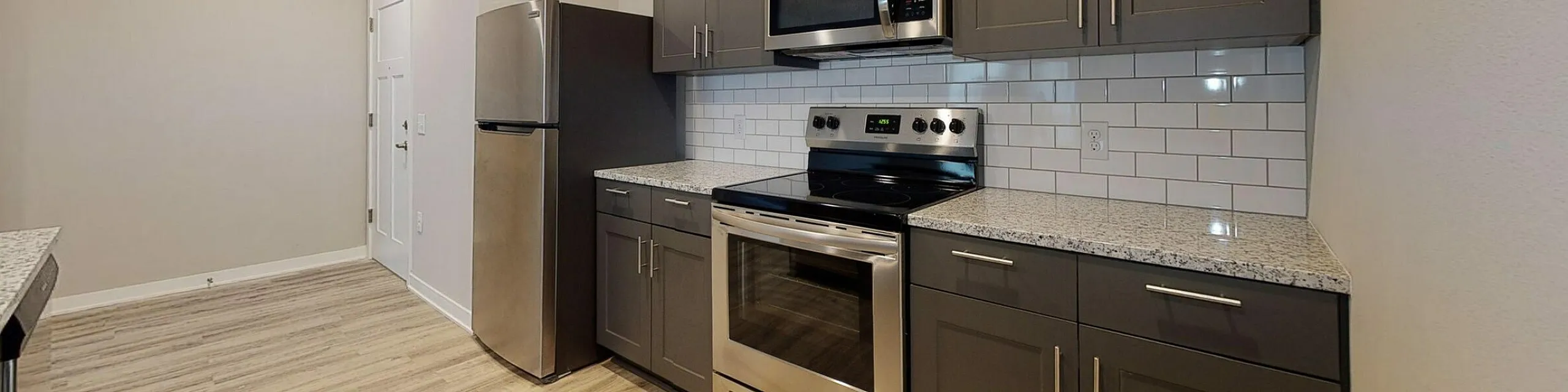 Modern kitchen with sleek stainless steel appliances, elegant dark cabinetry, and a luxurious granite countertop.