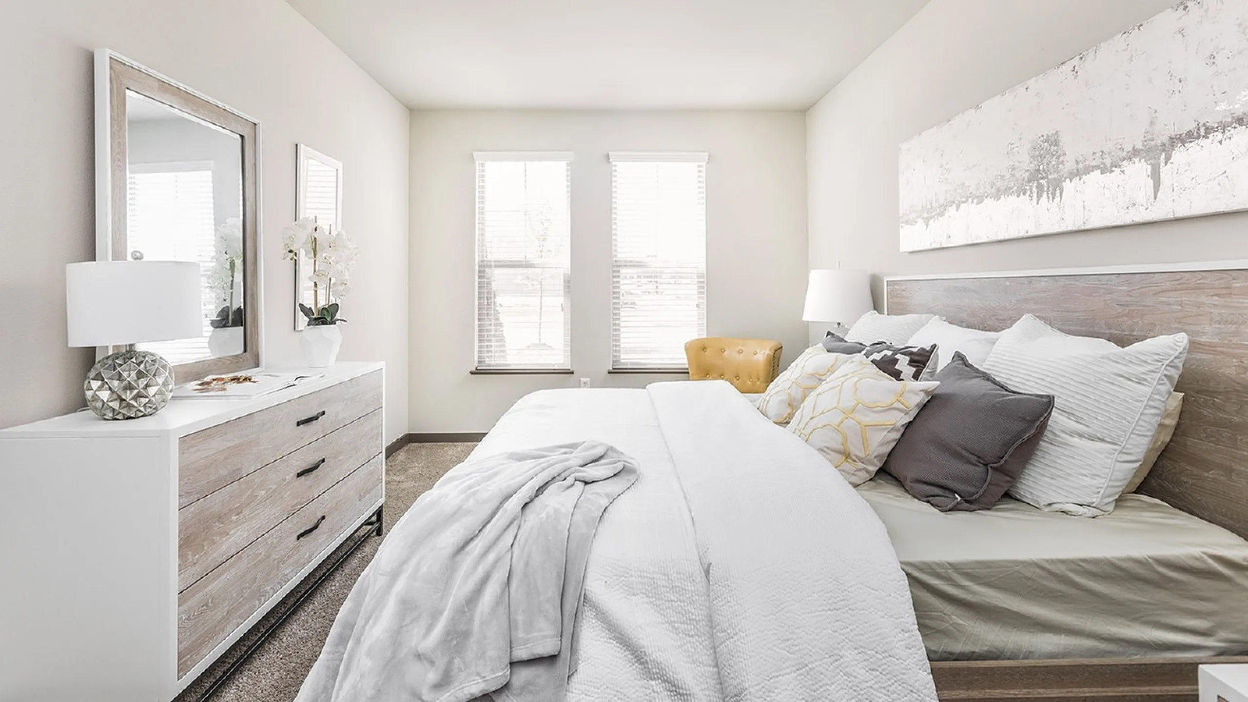 Bright and inviting bedroom with stylish decor, featuring a cozy bed with plush pillows, a chic dresser, and elegant artwork.