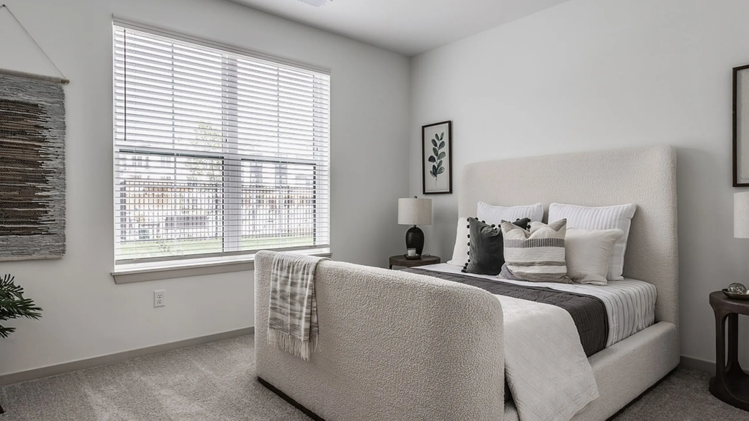Inviting bedroom with plush carpeting, modern decor, and abundant natural light through large windows.