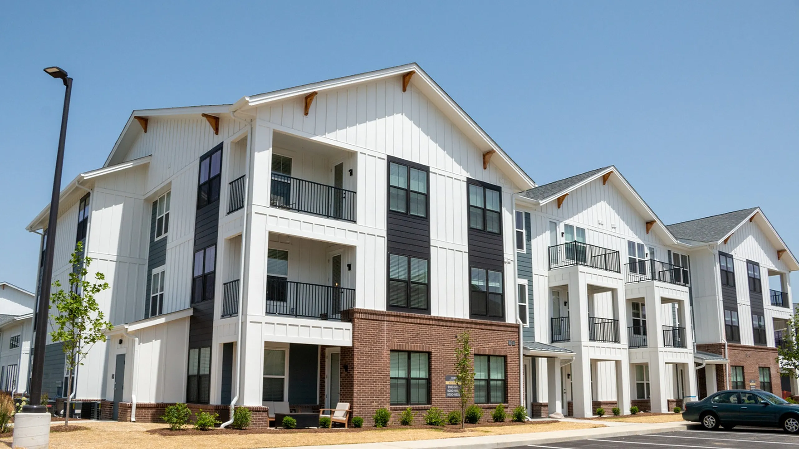 Modern apartment complex with elegant white siding and brick accents, featuring spacious balconies and well-maintained landscaping.
