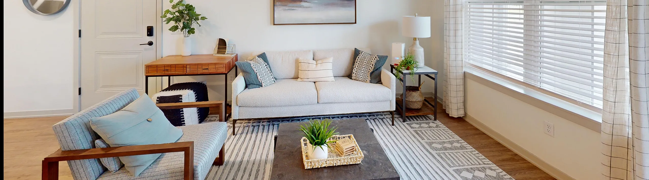 Bright and elegant living room with modern decor, featuring a cozy sofa, chic armchair, and stylish coffee table, all bathed in natural light from large windows.