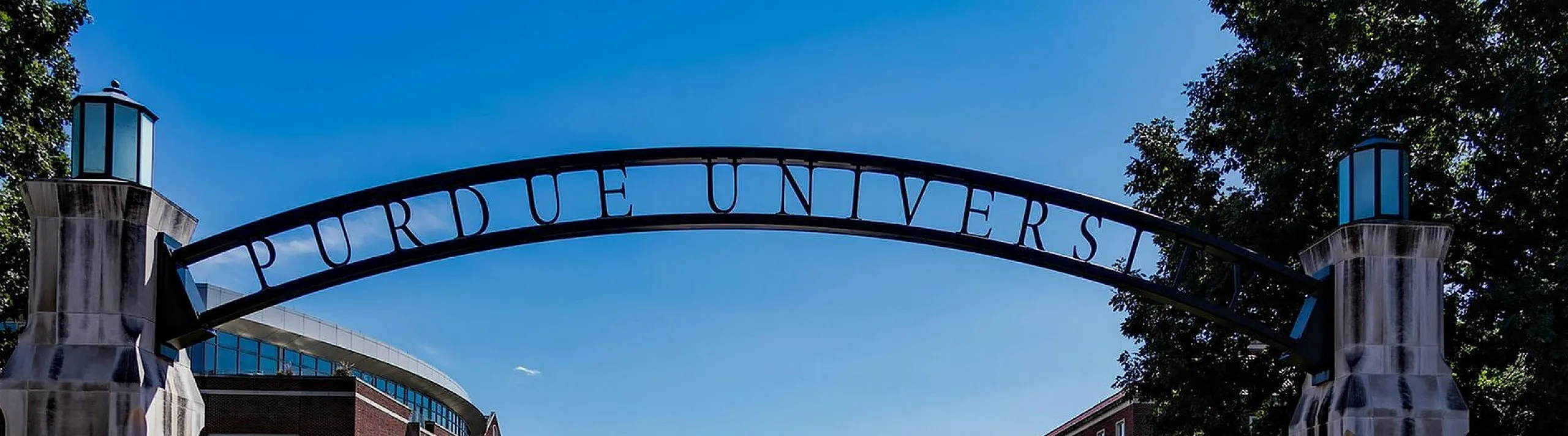 Inviting university entrance with iconic archway and beautifully landscaped surroundings under a clear blue sky.