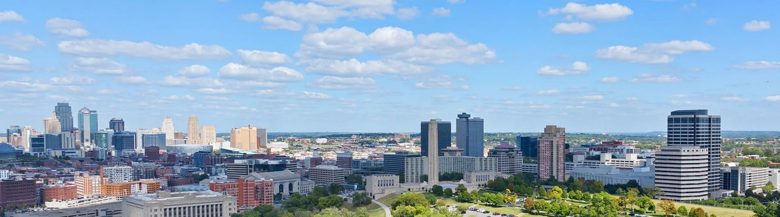 Stunning cityscape view showcasing a vibrant skyline and lush green park under a bright blue sky.