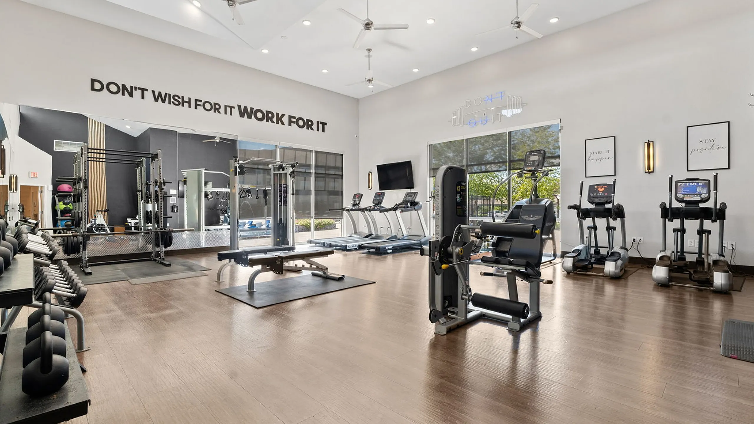Modern fitness center with state-of-the-art exercise equipment, motivational wall art, and bright natural lighting perfect for an invigorating workout.