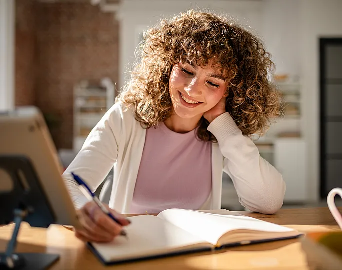 Bright and inviting home office scene with a cheerful woman writing in a notebook, enhancing productivity and creativity.