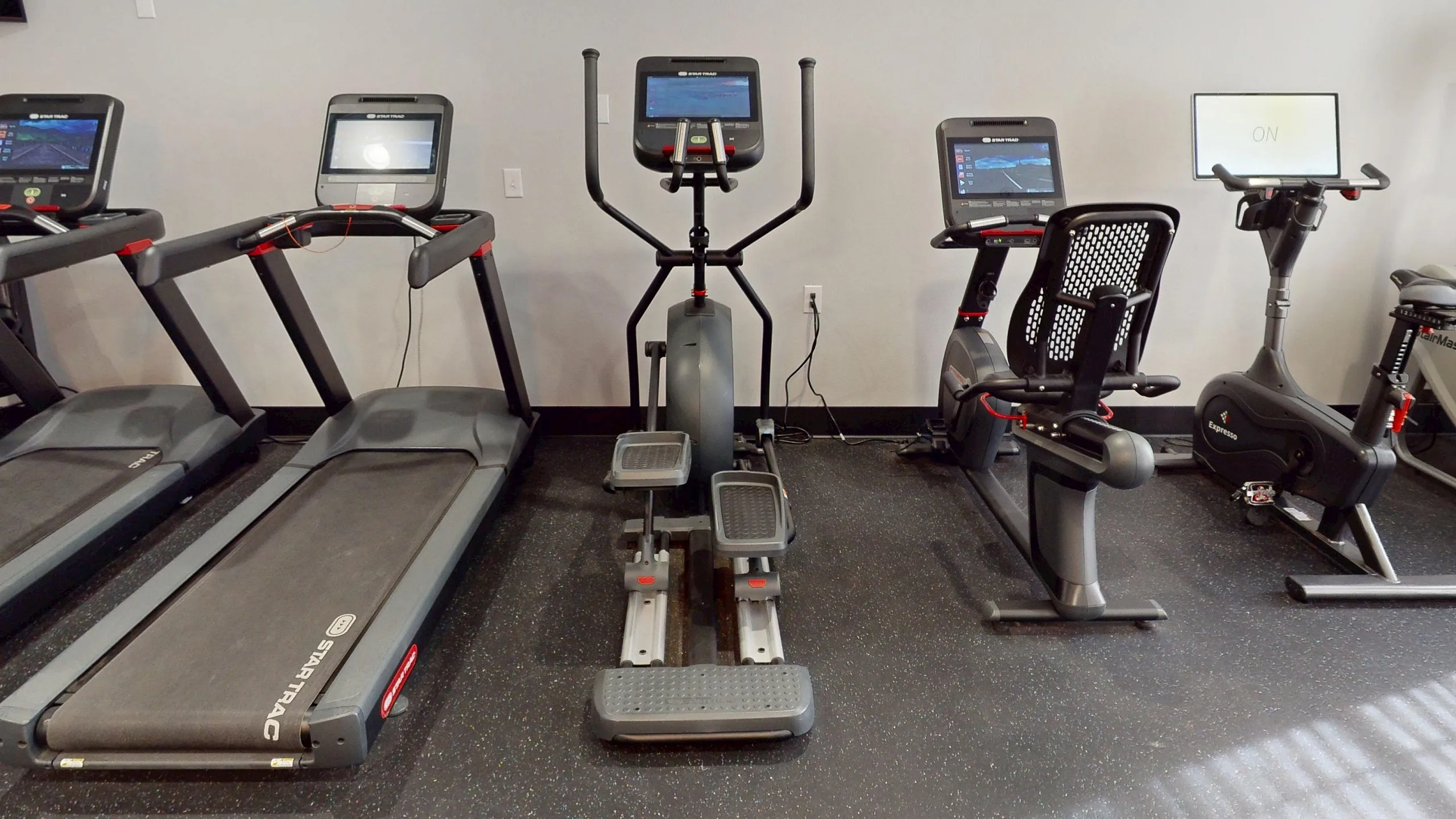 Modern fitness center featuring state-of-the-art treadmills, elliptical, and exercise bikes with interactive screens.