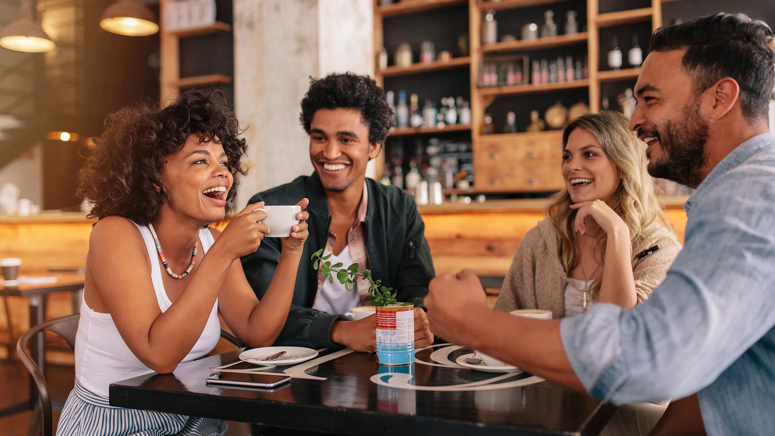 Group of friends joyfully enjoying coffee in a cozy cafe with a stylish, rustic ambiance.