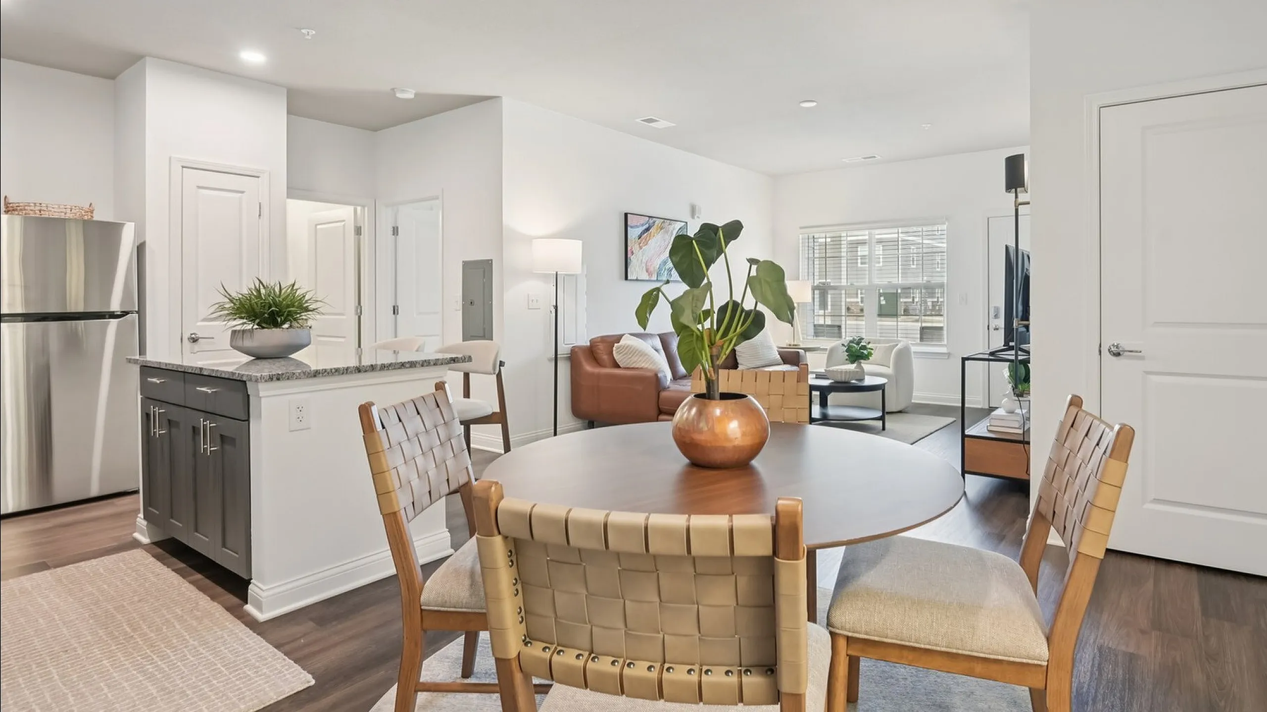 Modern apartment interior showcasing an open-concept living and dining area with stylish decor, featuring a cozy seating arrangement, elegant dining table, and a sleek kitchen with stainless steel appliances.