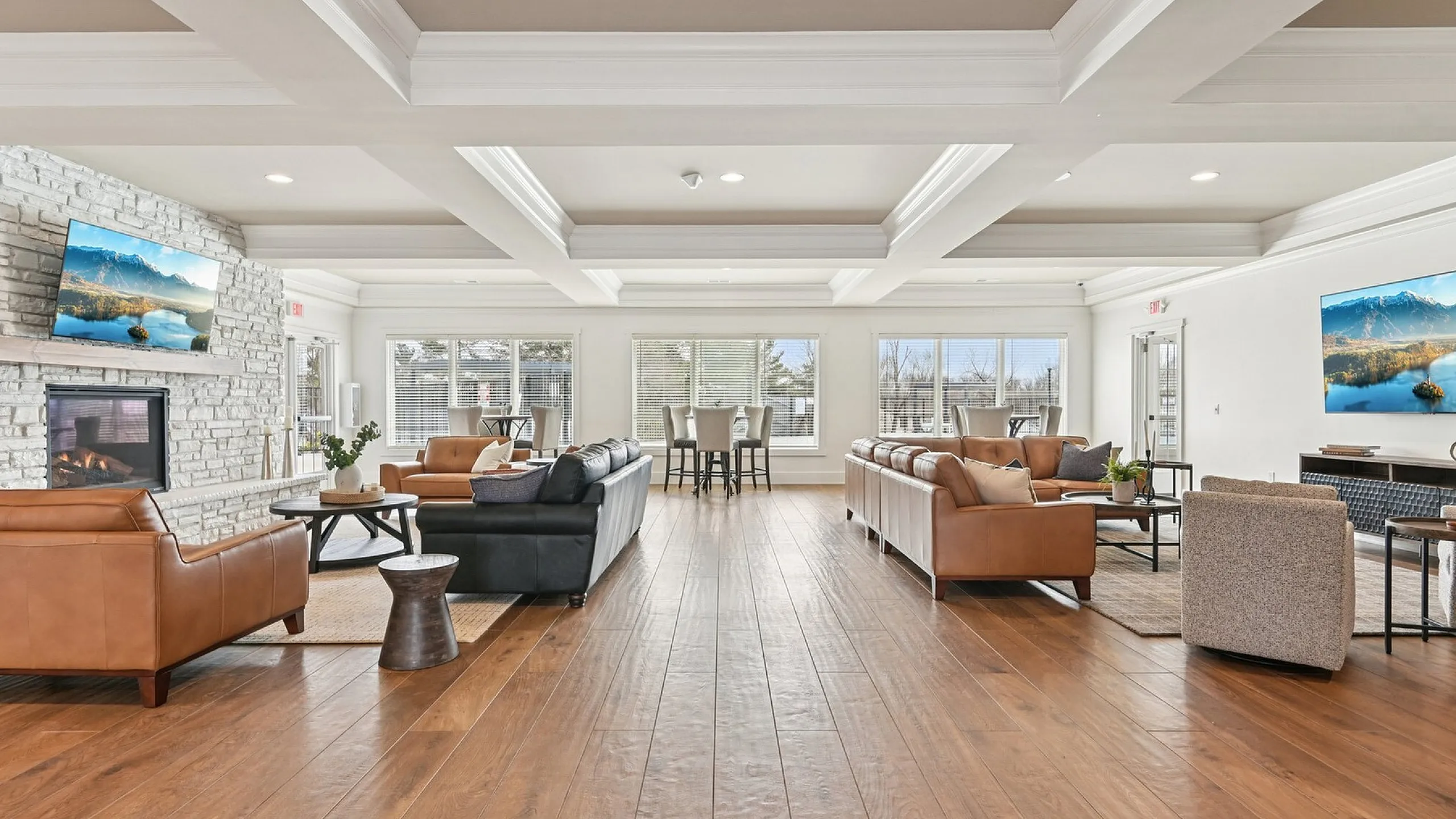 Luxurious open-concept living room with elegant leather sofas, a cozy stone fireplace, and large windows inviting natural light.