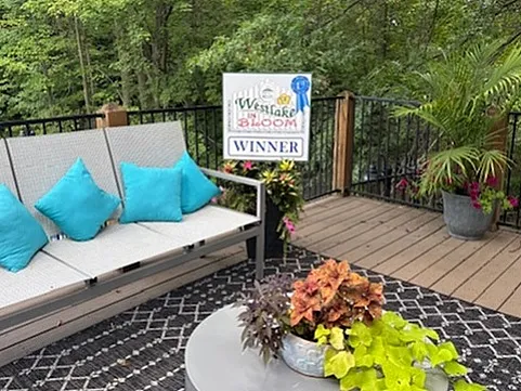 Charming outdoor patio with a stylish bench and vibrant turquoise pillows, surrounded by lush greenery, perfect for relaxation.