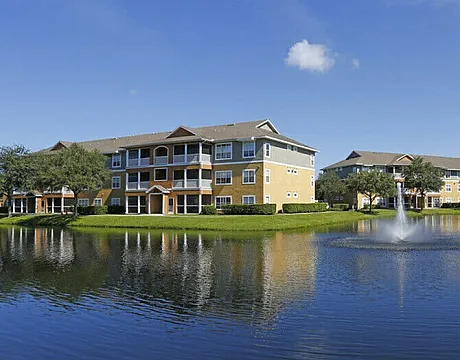 Charming apartment buildings with elegant architecture by a tranquil lake with a central fountain.