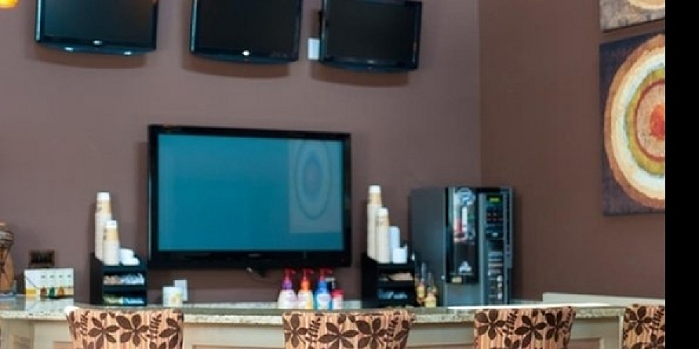 Stylish apartment lounge with floral-patterned bar stools and sleek televisions.