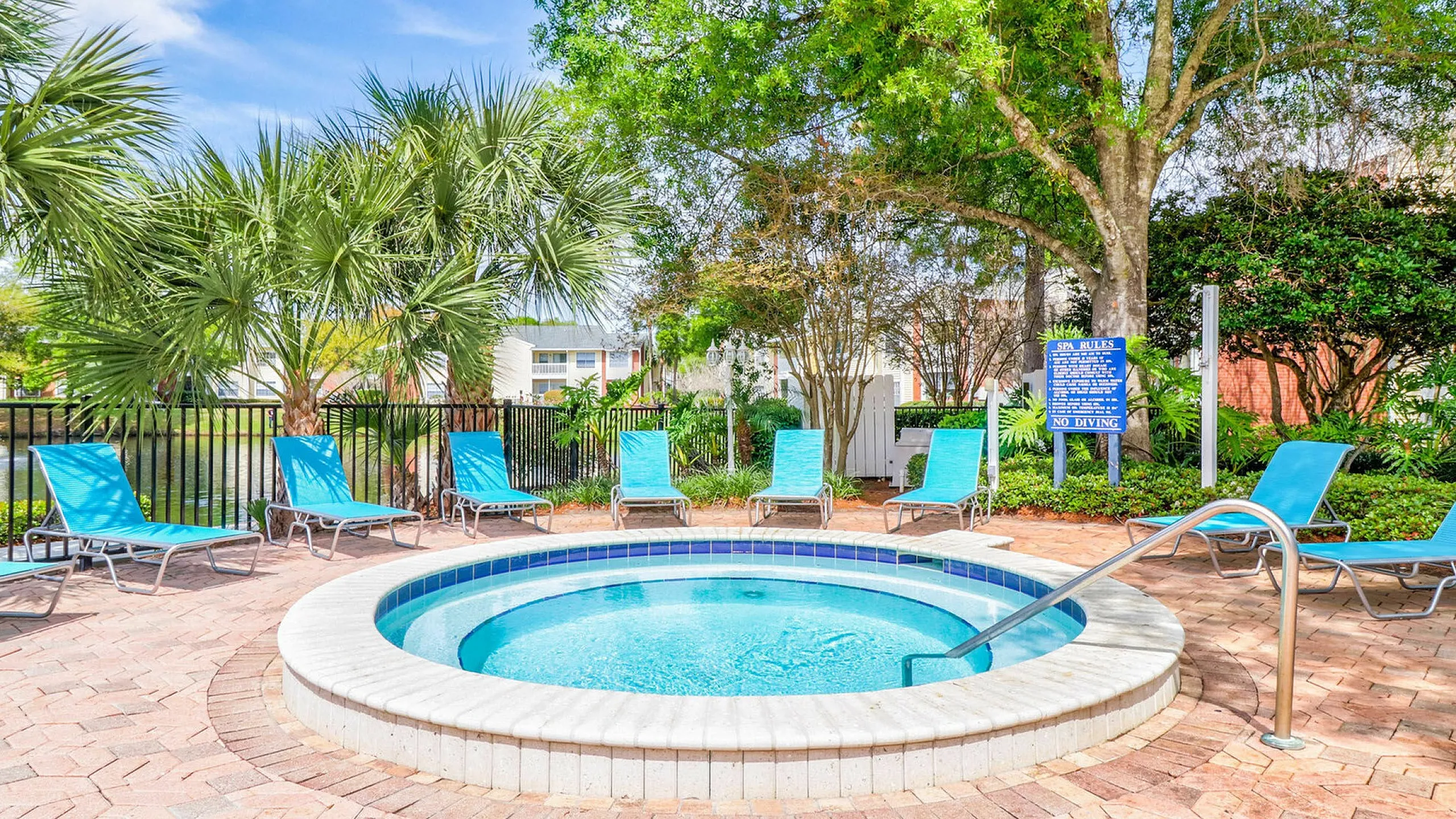 Inviting outdoor spa surrounded by blue lounge chairs and lush greenery.