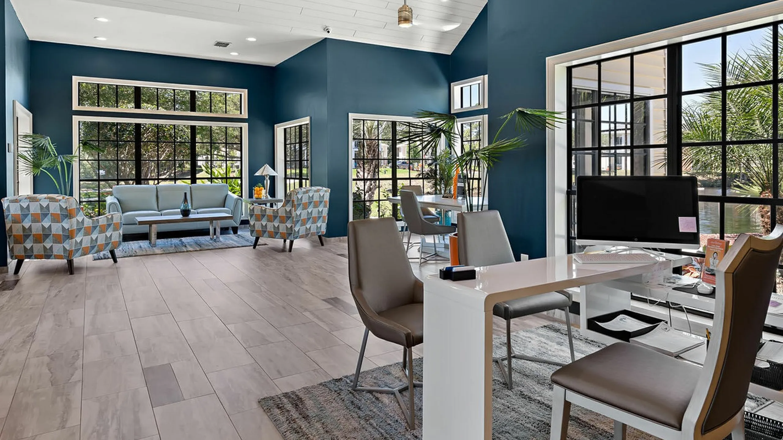 Chic office lounge area with vibrant blue walls, modern furniture, and large windows.