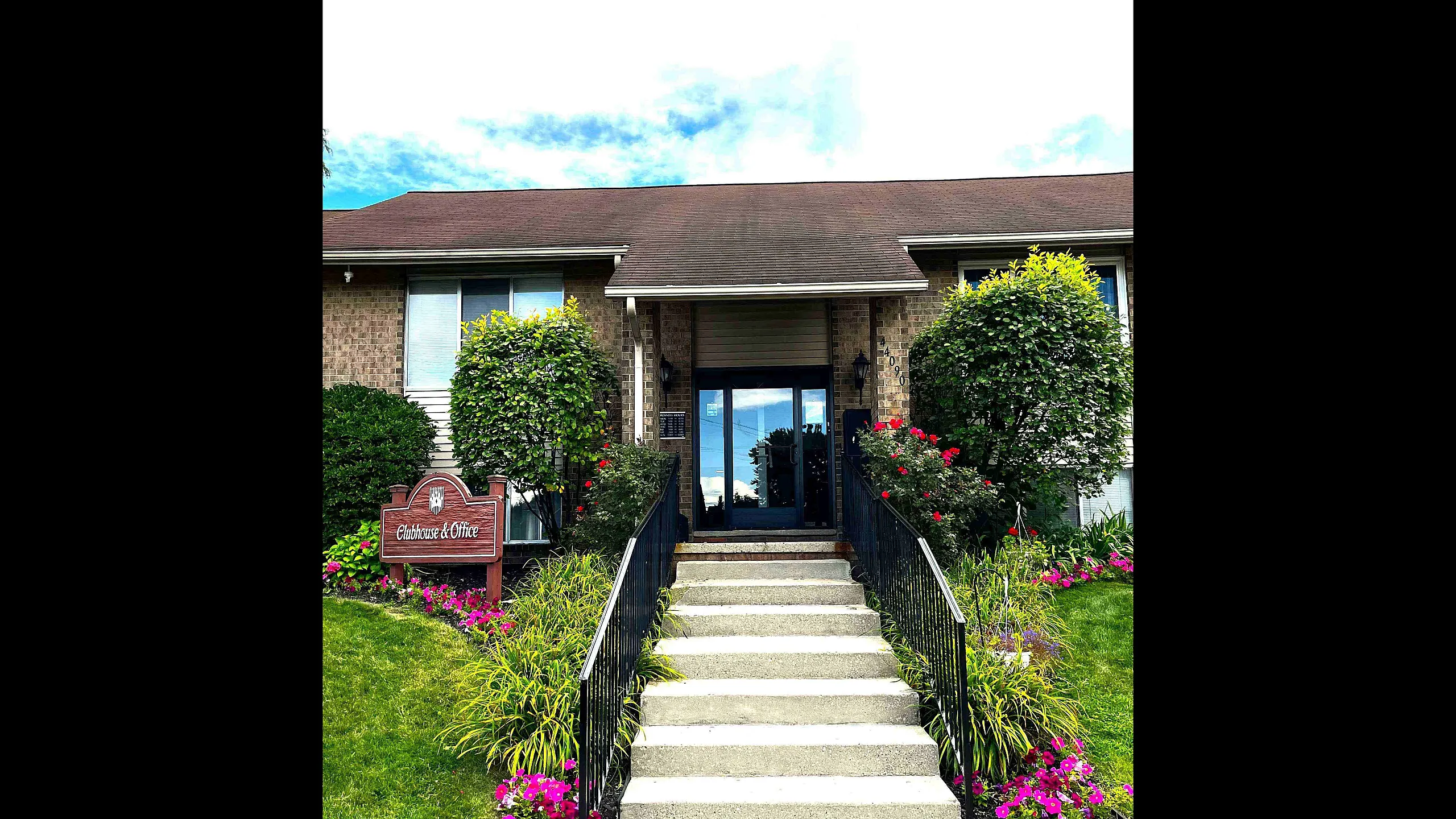 Inviting entrance to a clubhouse with blooming flowers and lush greenery.