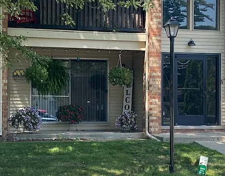 Inviting apartment patio with lush hanging plants and cozy outdoor seating area.