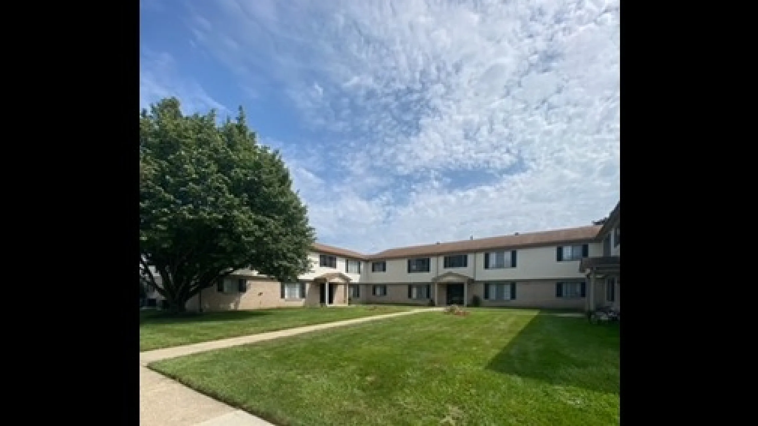 Inviting apartment complex with lush green lawns and a picturesque courtyard.