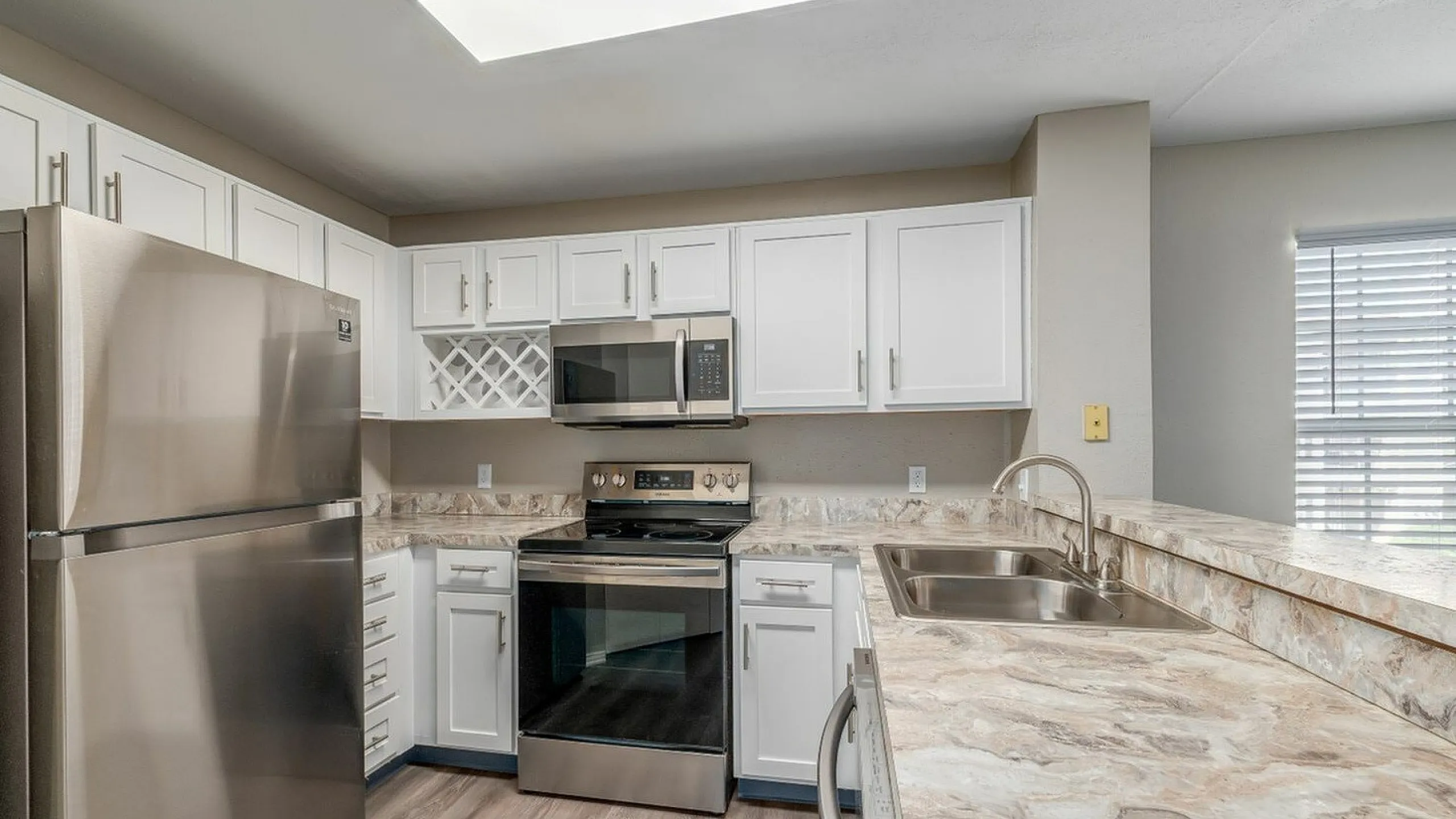 Modern kitchen with stainless steel appliances, sleek white cabinetry, and a stylish marble countertop.