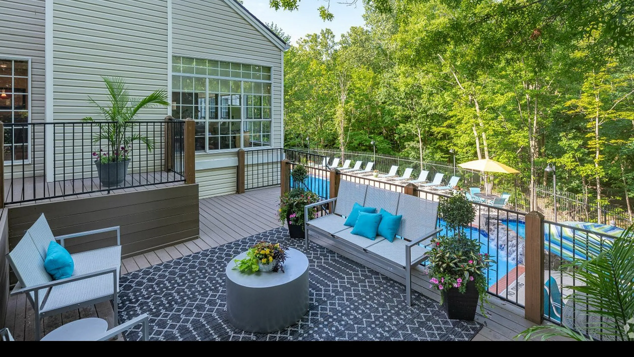 Charming outdoor terrace with stylish seating, lush plants, and a view of a serene pool amidst vibrant greenery.