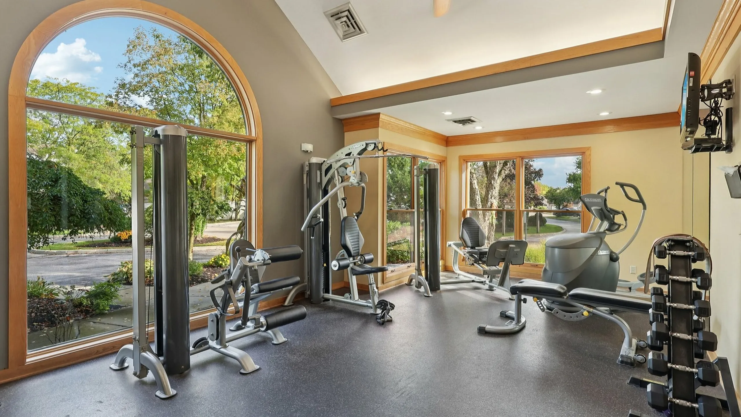Bright and modern fitness room featuring state-of-the-art exercise equipment and large arched windows with scenic views.
