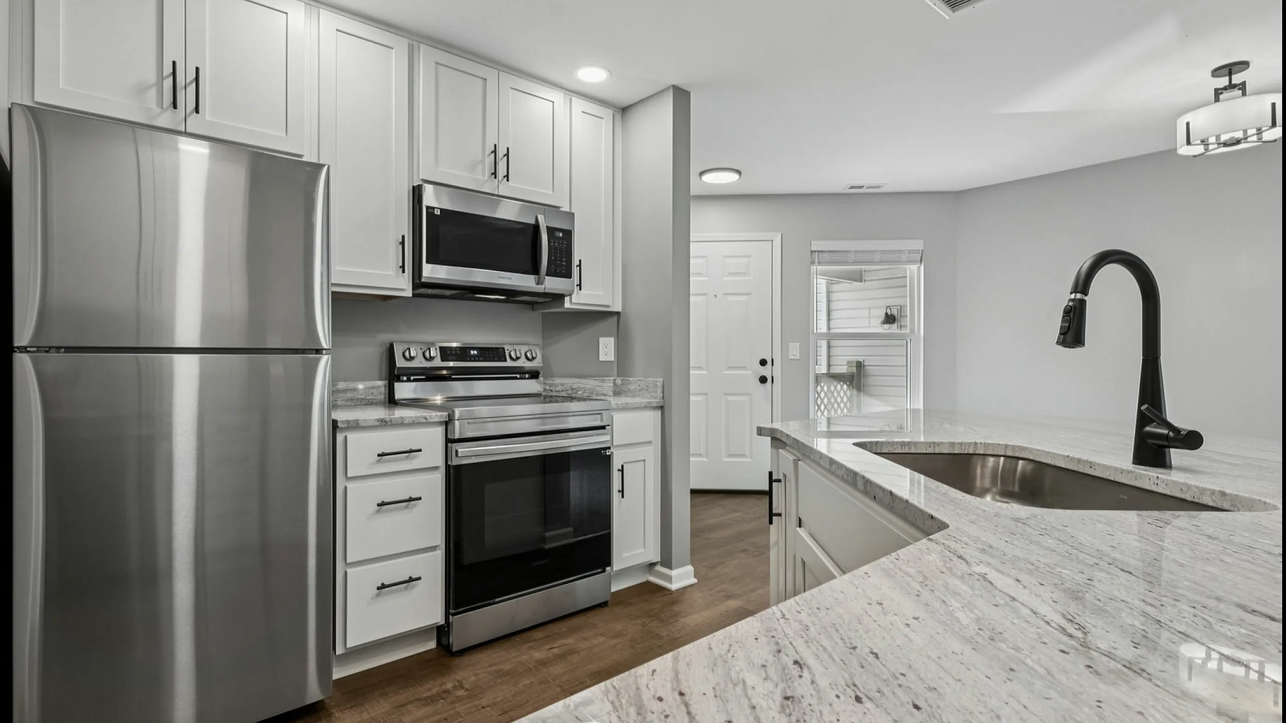 Modern kitchen with sleek stainless steel appliances, elegant granite countertops, and contemporary white cabinetry offering a sophisticated culinary space.