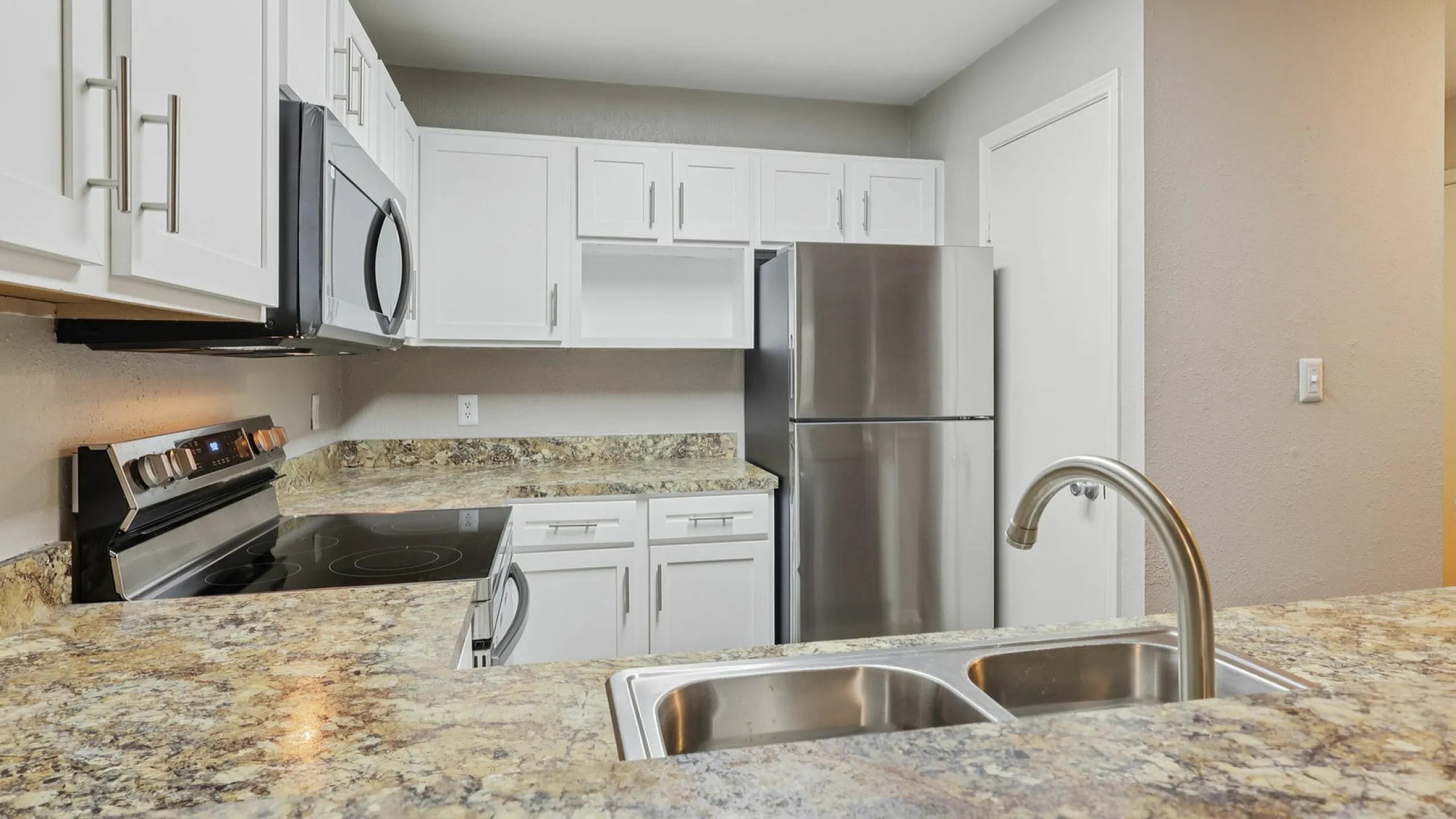 Modern kitchen with sleek stainless steel appliances, elegant white cabinetry, and granite countertops.