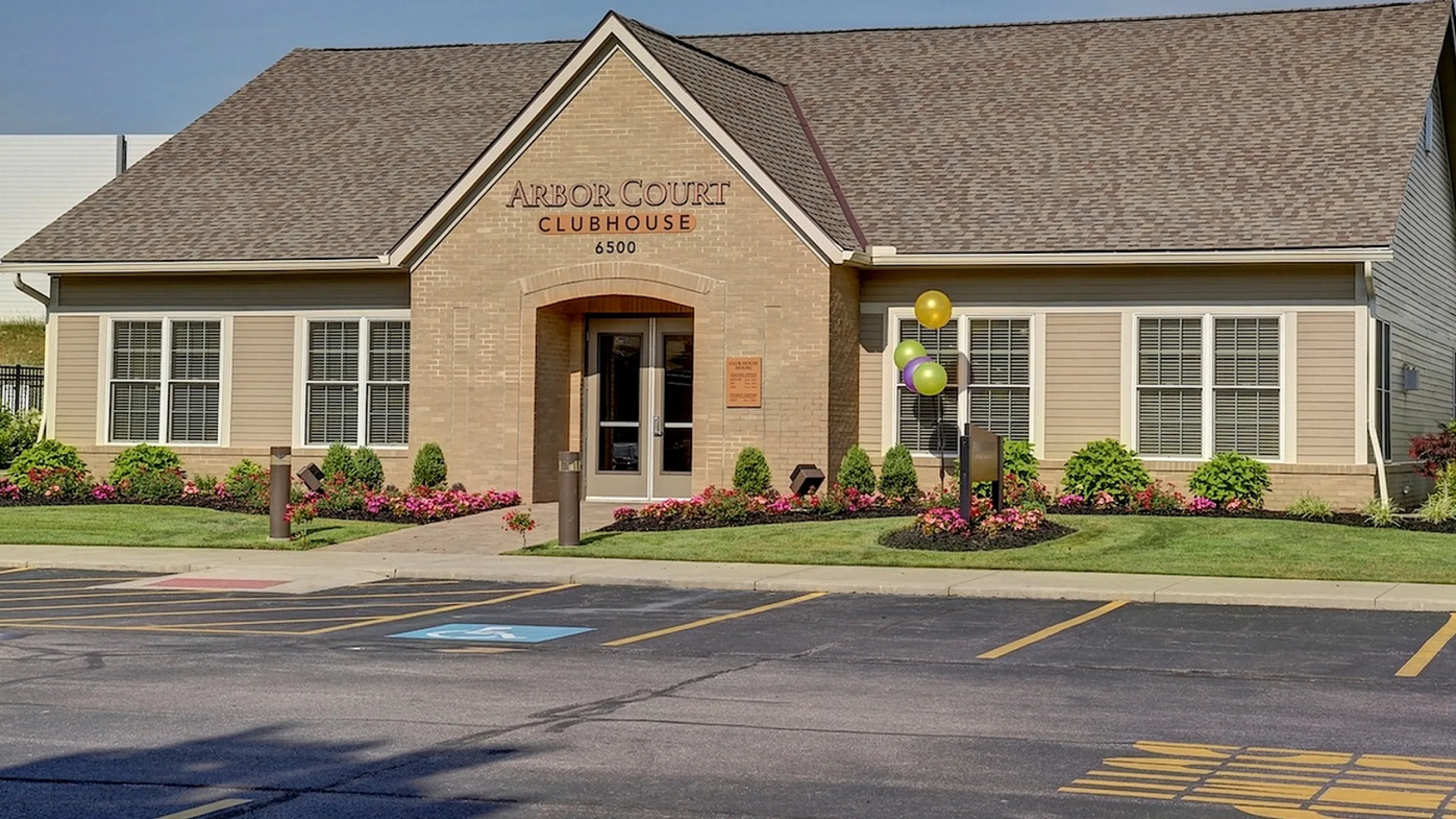 Inviting clubhouse exterior with manicured landscaping, vibrant flowers, and colorful balloons, perfect for community gatherings.