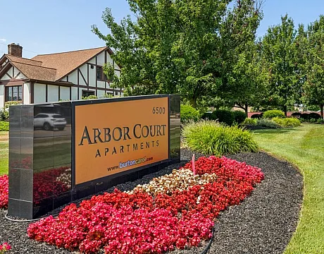 Inviting entrance to Arbor Court Apartments featuring a beautifully landscaped garden with vibrant flowers and well-maintained greenery.