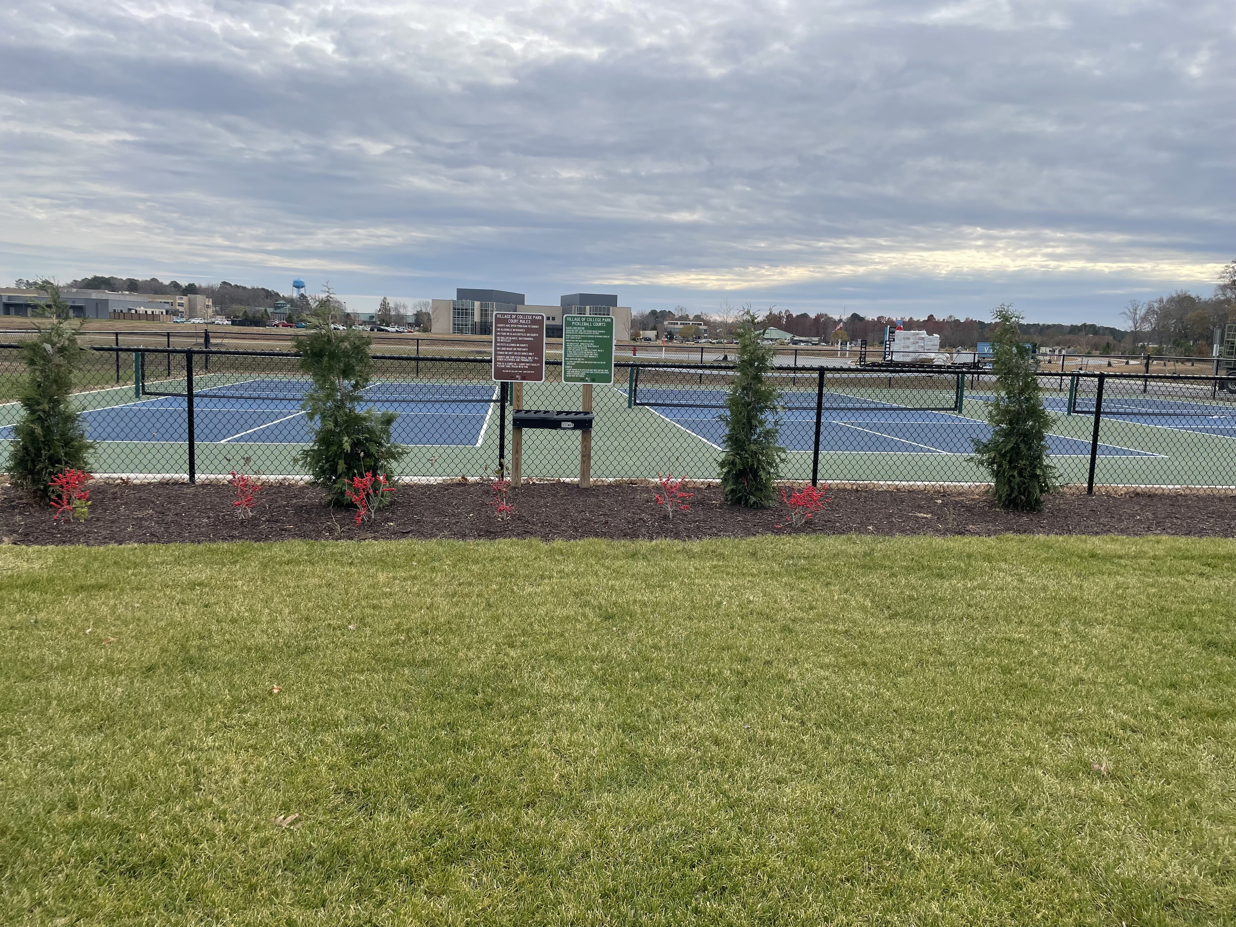 Beautiful outdoor tennis courts surrounded by lush greenery and vibrant landscaping, offering a perfect spot for sports enthusiasts.