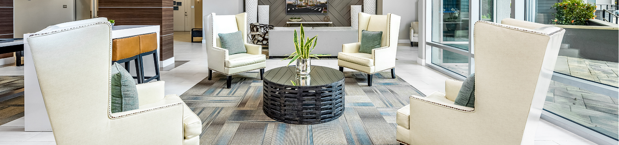 Modern apartment lobby with sleek armchairs, stylish coffee table, and large windows.