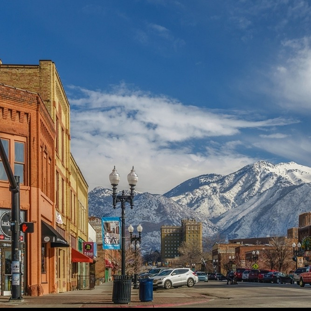 Charming downtown street with vibrant brick buildings, framed by stunning snow-capped mountains under a clear blue sky.