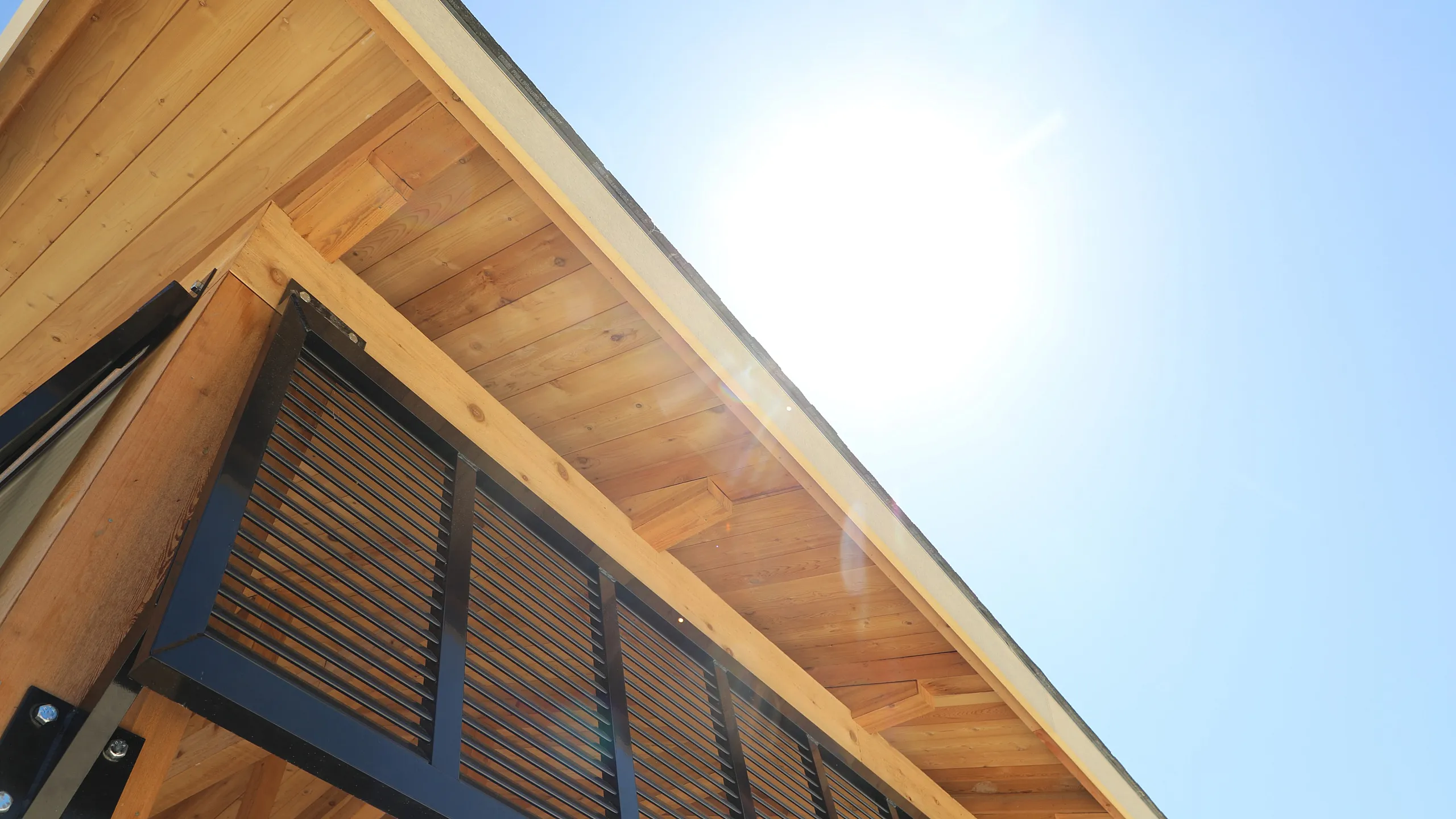 Modern wooden architecture with sleek slatted design under bright blue sky and sunlight.