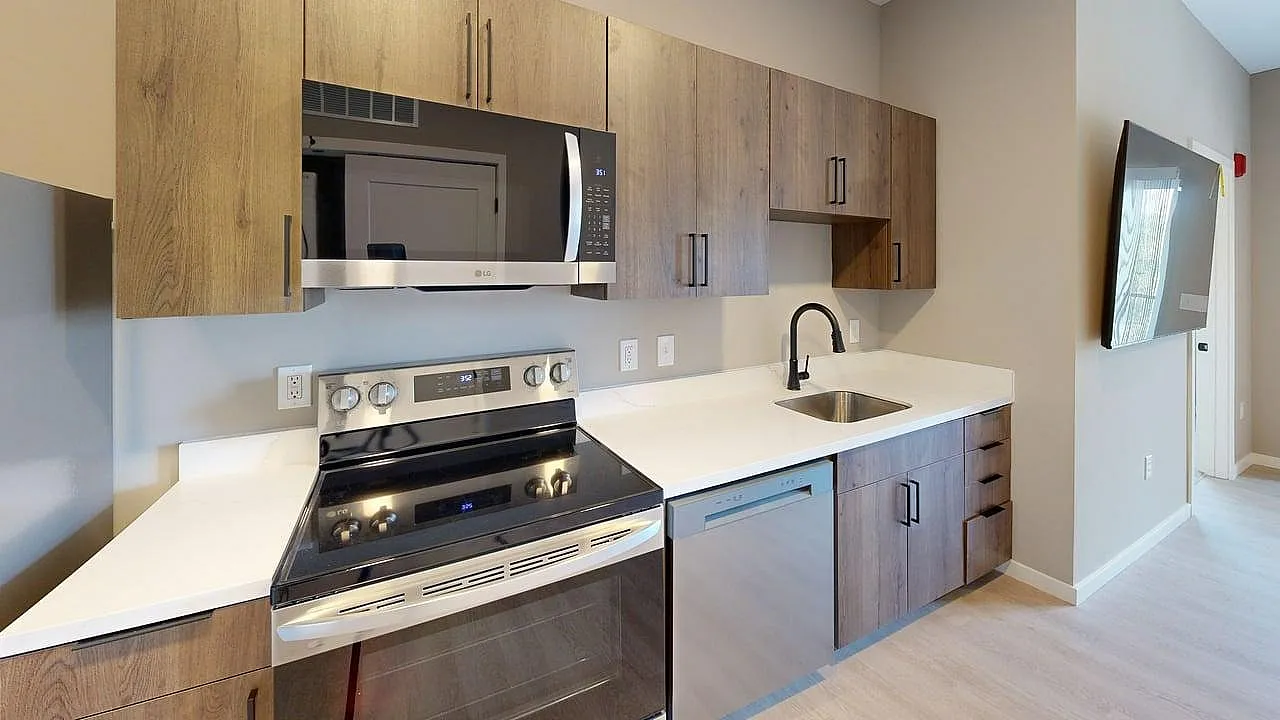Modern kitchen with sleek appliances, stylish wood cabinetry, and pristine countertops in a contemporary apartment.