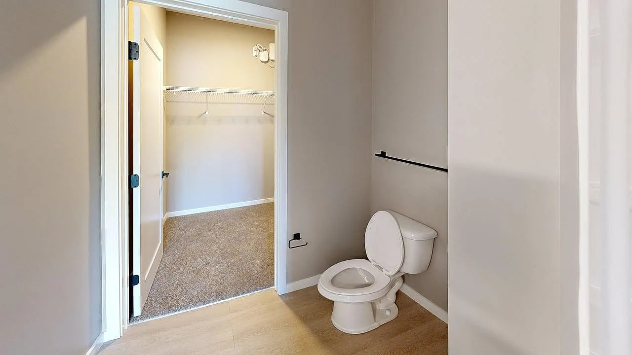 Inviting bathroom showcasing a modern design with sleek flooring, connected to a spacious walk-in closet.