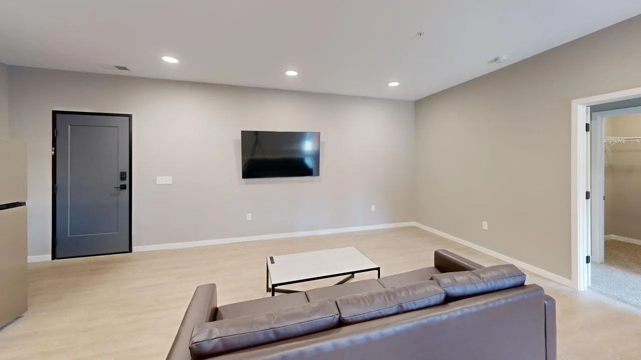 Modern living room with sleek leather sofa, wall-mounted TV, and minimalist decor creating an inviting space.