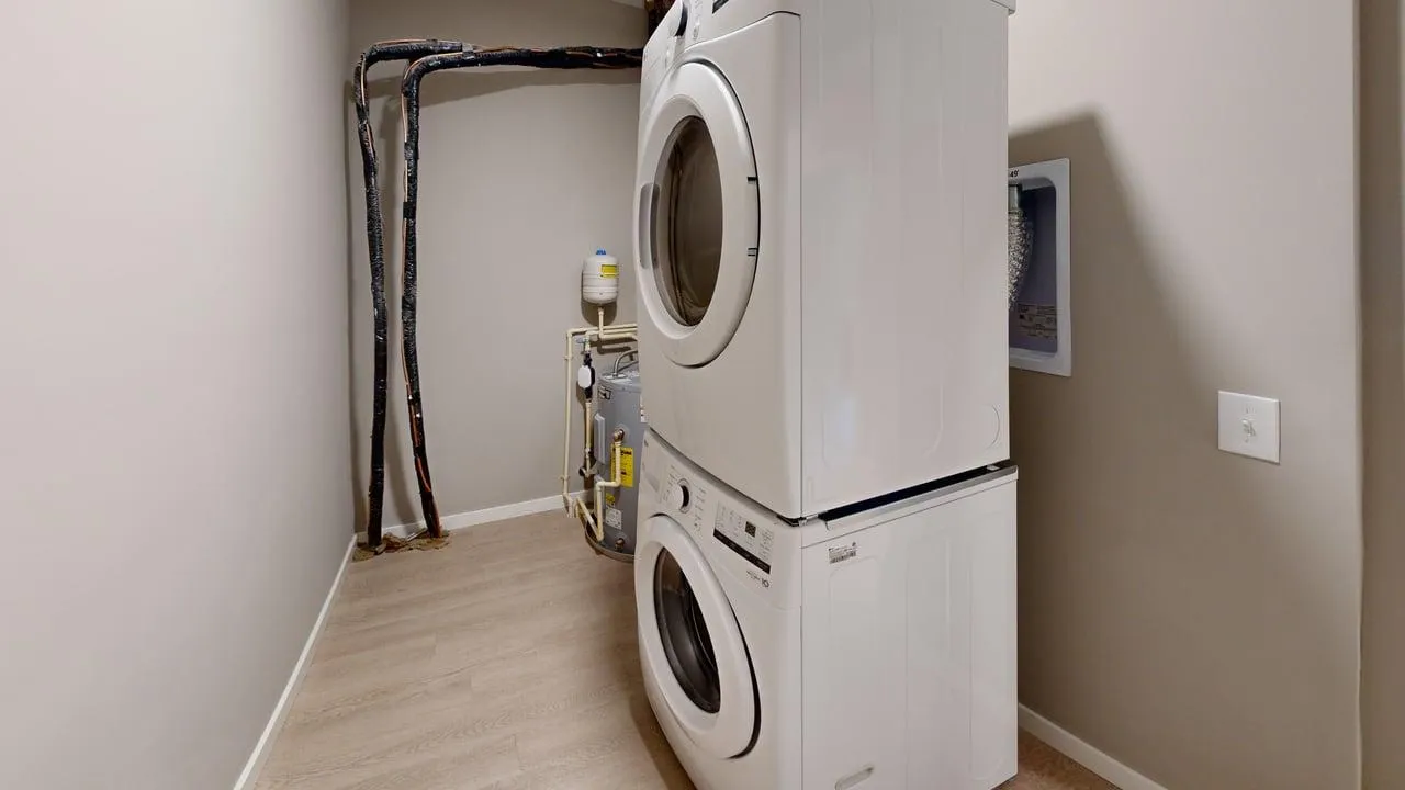 Modern laundry room with stacked washer and dryer units, featuring sleek appliances and efficient design.