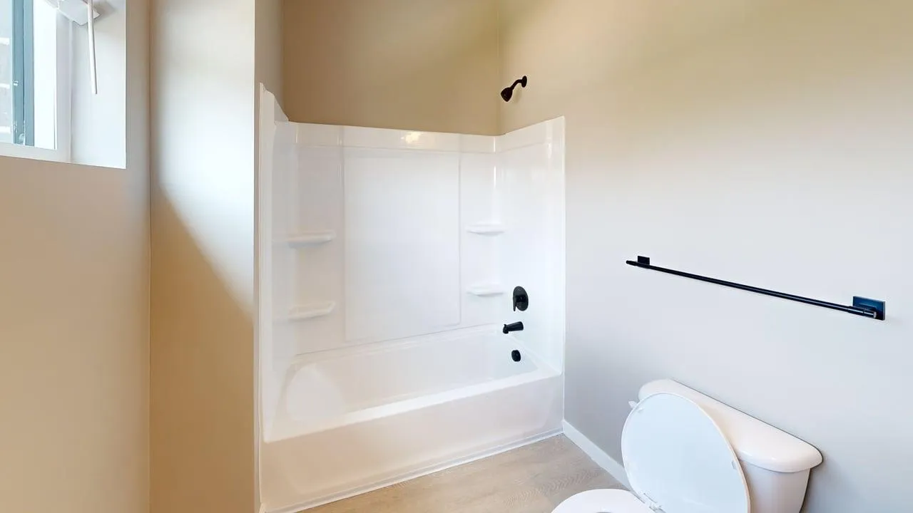 Bright, modern bathroom with a sleek white bathtub, subtle fixtures, and natural light.