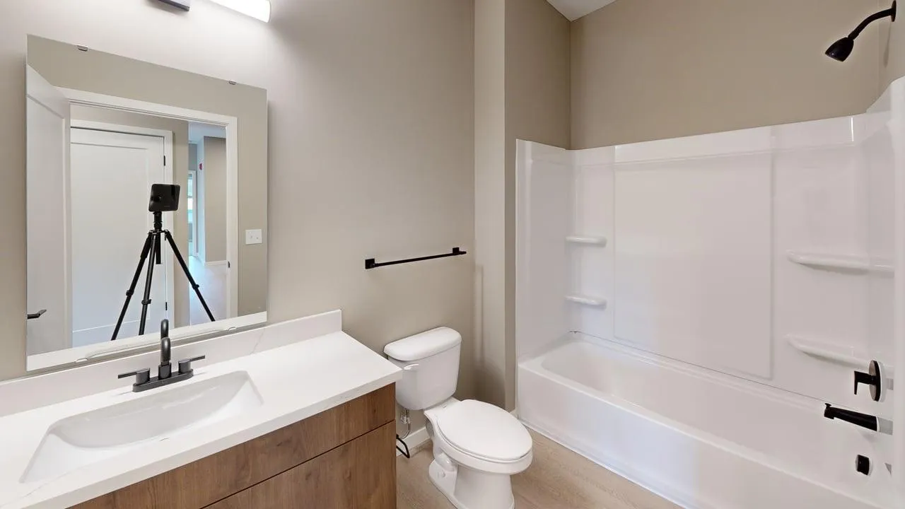 Modern bathroom with sleek fixtures, vanity mirror, and a full-size bathtub in a bright and inviting space.
