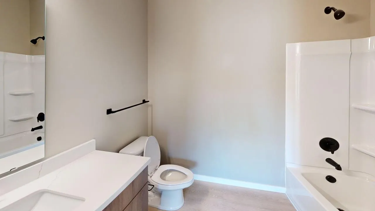 Modern bathroom with sleek fixtures, featuring a white vanity, spacious bathtub, and elegant neutral tones.