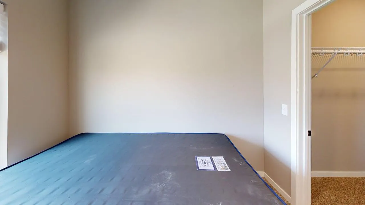 Cozy bedroom with a minimalist design featuring a compact closet and neutral wall tones.