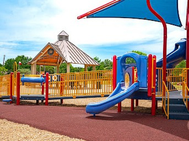 Vibrant and spacious playground featuring colorful slides, climbing structures, and a shaded picnic area, perfect for family fun.
